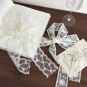 Detailed embroidery on vintage-style French lace ribbons with floral patterns on wood surface