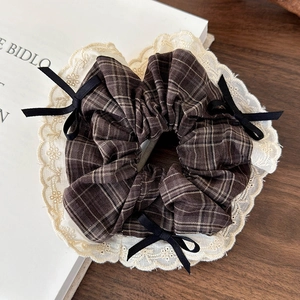 Detailed close-up of brown plaid scrunchie with cream lace trim and small black bows