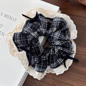 Detail of retro plaid hair scrunchie with lace edges and small black bows