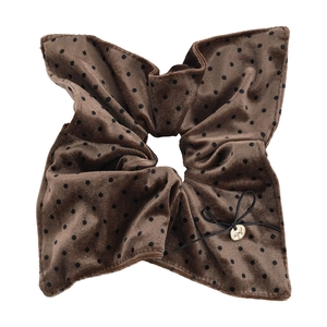 Detailed macro view of brown velvet polka dot scrunchie with lace and gold logo pendant