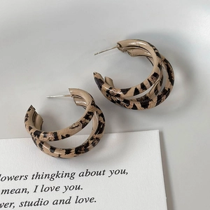 Detail of double-layer C-shaped earrings with leopard print and polished finish