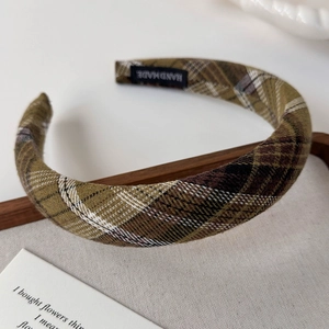 Detail of a handmade plaid headband featuring classic green and brown checkered fabric texture