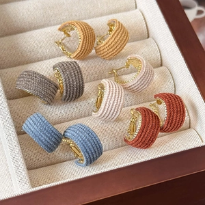 Detailed macro view of woven fabric hoop earrings in various vintage autumn colors
