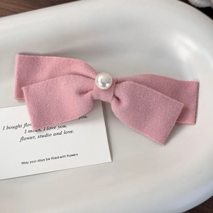 Nahaufnahme der rosa Stoffschleife mit Perle auf einem weißen Keramiktablett