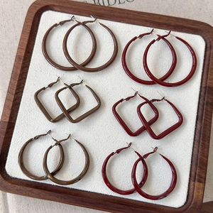 Macro detail of geometric hoop earrings in brown and burgundy resin with glossy finish