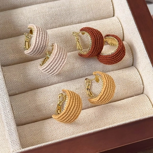 Close-up of retro fabric-wrapped C-shape hoop earrings in cream, caramel, and ginger colors