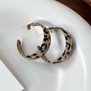 Close-up of leopard print C-shape earrings on a white textured tray for a chic look