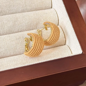 Macro shot of caramel fabric-wrapped C-shape earrings with vintage golden beaded edges