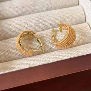 Close-up of golden C-shaped hoop earrings with yellow corduroy fabric in a jewelry box