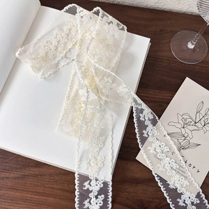 Detailed view of delicate off-white floral lace ribbon on a rustic wooden background