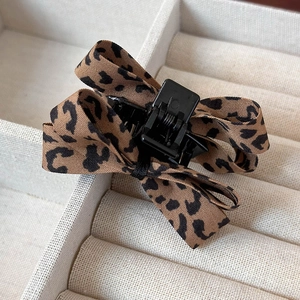 Gros plan d'une pince à cheveux avec nœud léopard dans un coffret à bijoux blanc élégant