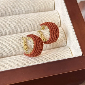 Detail of red tweed fabric texture on C-shaped gold hoop earrings for women