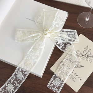Detail view of retro cream lace ribbon with floral embroidery tied in a bow on vintage books