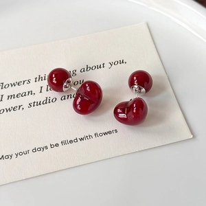 Detailed close-up of dark red cherry-shaped heart stud earrings on a white card