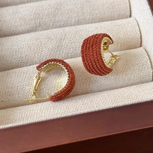 Detailed close-up of retro red-brown woven fabric C-shaped hoop earrings in jewelry box
