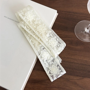 Detailed macro view of white floral lace embroidery ribbon with scallop edges on book