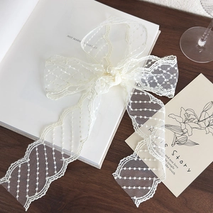 Detail shot of vintage cream lace ribbon with delicate wave edges and polka dot embroidery