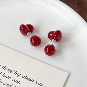 Elegant cherry red heart ball stud earrings on a white ceramic plate with a card