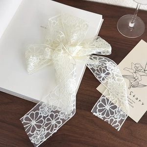 Detail of vintage white floral lace hair ribbon bow on a rustic wooden tabletop