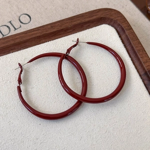Macro shot of retro burgundy geometric hoop earrings on textured wooden background