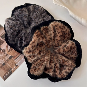 Detail view of two faux fur leopard print scrunchies in dark grey and brown plush