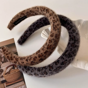 Detail showing two plush leopard print headbands in brown and gray on a ceramic bowl