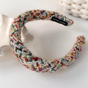 Detail eines mehrfarbig gestrickten Stirnbandes mit Hand-made-Etikett und Wolltextur