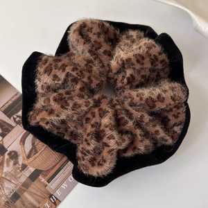 Detail of plush leopard print scrunchie with soft faux fur and black velvet trim edge