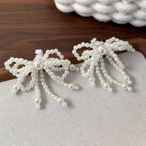 Détails de deux clips à chaussures en perles en forme de nœud avec pompons élégants