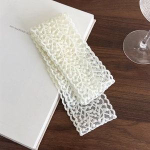 Close-up of ivory lace ribbon showing intricate hollow floral texture on wooden table