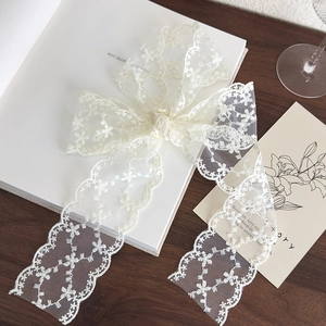 Close-up of white floral lace ribbon with scalloped edges on a wooden table decor