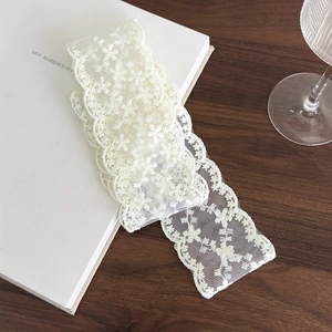 Detailed macro view of white floral lace ribbon with delicate hollow embroidery texture