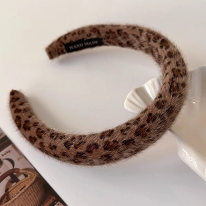 Close-up of leopard print plush headband featuring a hand made tag on soft faux fur