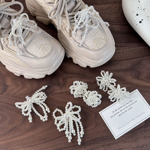 Elegant white pearl shoelace charms with bow and flower designs on sneakers