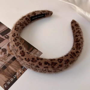 Detail of plush leopard print headband with handmade label on a soft fabric texture