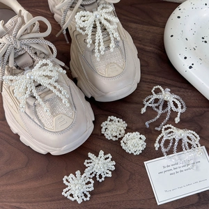 Elegant pearl and bead shoe charms with bow and floral designs on beige sneakers