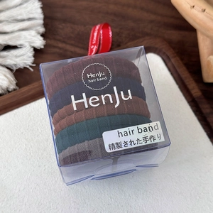 Macro-opname van 5 elastische haarbanden van geribbelde stof in een luxe doosje