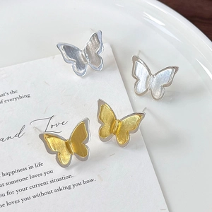 Detail of two pairs of 3D brushed metal butterfly stud earrings in silver and gold finish