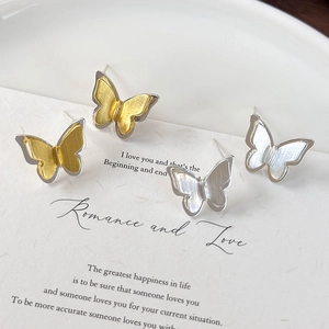 Detailed view of brushed metal butterfly earrings in gold and silver on a white card
