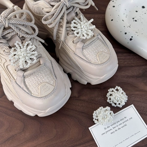 Detail of elegant pearl snowflake buckles on beige leather and mesh sneakers