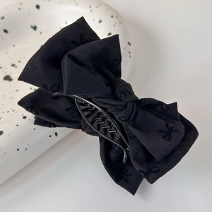 Détail d'une pince à cheveux en tissu noir avec broderie papillon élégante et discrète