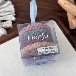Detail van vijf gekleurde naadloze haarelastiekjes in een transparante geschenkdoos
