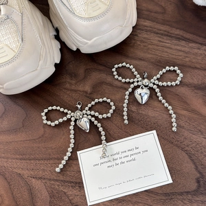 Gros plan de charms pour chaussures en argent avec nœuds et cœurs sur fond bois