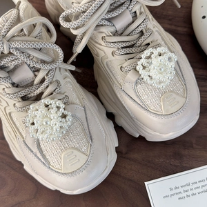 Detail view of pearl flower charms and crystal bead decorations on beige platform sneakers