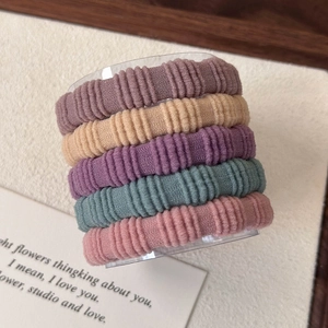 Detail van vijf geribbelde naadloze haarelastiekjes in zachte pastelkleuren op houder