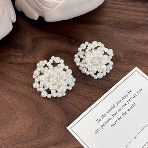 Detailed macro view of handmade cluster pearl flower shoe charms on a dark wood background