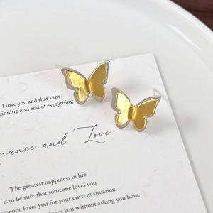 Close-up of dual-layer butterfly earrings with golden brushed texture and silver base