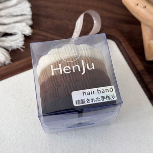 Detail van 5 naadloze haarelastiekjes in aardetinten in een transparante geschenkdoos