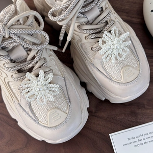 Detail of faux pearl snowflake charms on cream platform sneakers with tweed texture