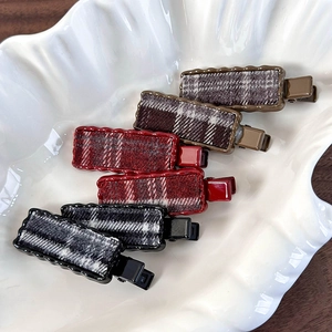 Gros plan de six pinces à cheveux à carreaux de style vintage britannique sur plateau